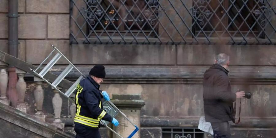 Einsatzkräfte der Polizei gehen mit einer Leiter im Bärengarten vor den Gitterfenstern des Grünen Gewölbes am Residenzschloss entlang. Foto: Sebastian Kahnert/dpa-Zentralbild/dpa