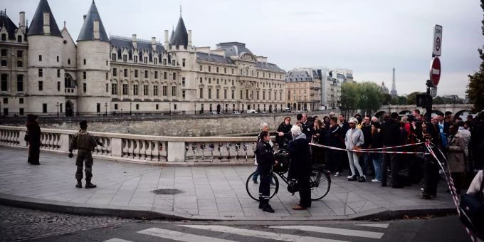 Schaulustige stehen hinter einer Absperrung, die von Polizisten gesichert wird. Messerattacke in Paris