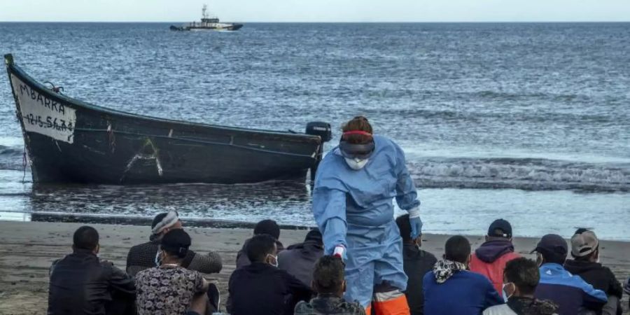 Migranten aus Marokko lassen ihre Temperatur messen, nachdem sie mit einem Holzboot an der Küste von Gran Canaria angekommen sind. Foto: Javier Bauluz/AP/dpa
