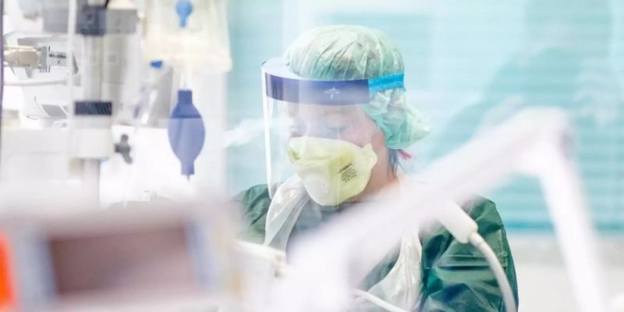 Eine Krankenpflegerin in einem Krankenzimmer auf der Intensivstation des Uniklinikums in Essen. Foto: Marcel Kusch/dpa