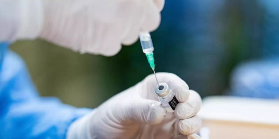 Ein Infektiologe zieht in einem Seniorenheim eine Spritze mit Impfstoff gegen das Coronavirus auf. Foto: Guido Kirchner/dpa