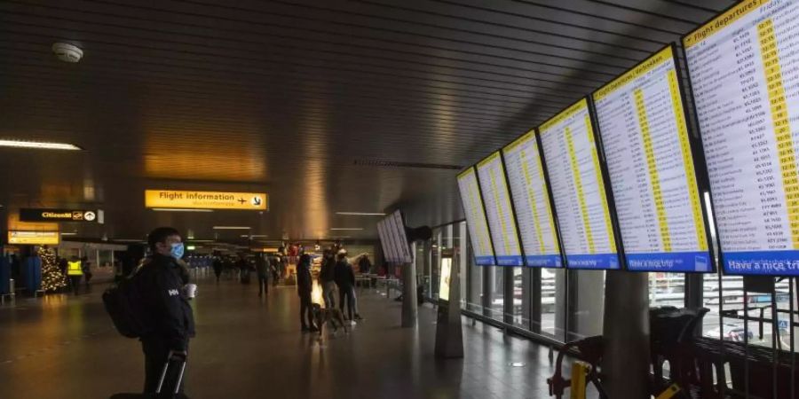 Ein Reisender schaut auf die Anzeigetafeln mit den Abflügen am Flughafen Schiphol bei Amsterdam. Foto: Peter Dejong/AP/dpa/Archivbild