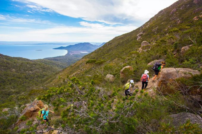 Der Freycinet Experience Walk ist eine Tour von vier Tagen, auf der sich die wilde Küste Tasmaniens hautnah entdecken lässt. Wandergruppe Berg hoch Australien