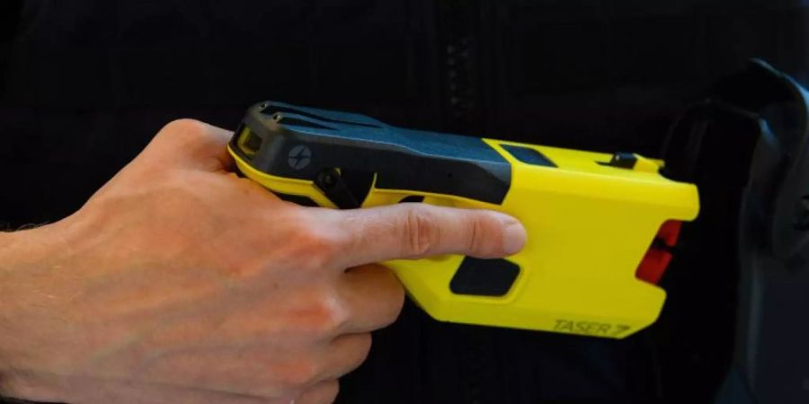 Ein Polizeibeamter präsentiert einen Taser. Foto: Soeren Stache/dpa-Zentralbild/dpa