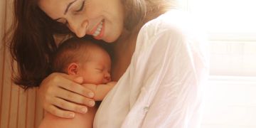 Mutter hält Neugeborenes im Arm