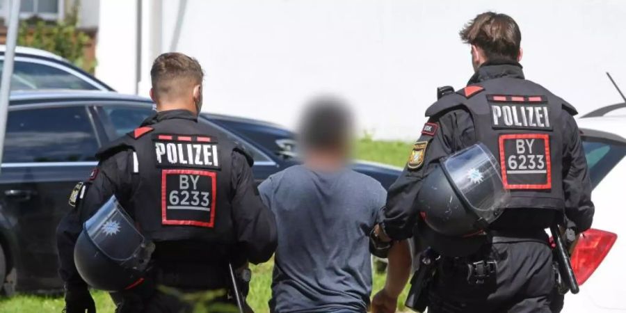 Zwei Einsatzkräfte der Polizei führen in Miesbach einen Tatverdächtigen ab. Foto: Tobias Hase/dpa