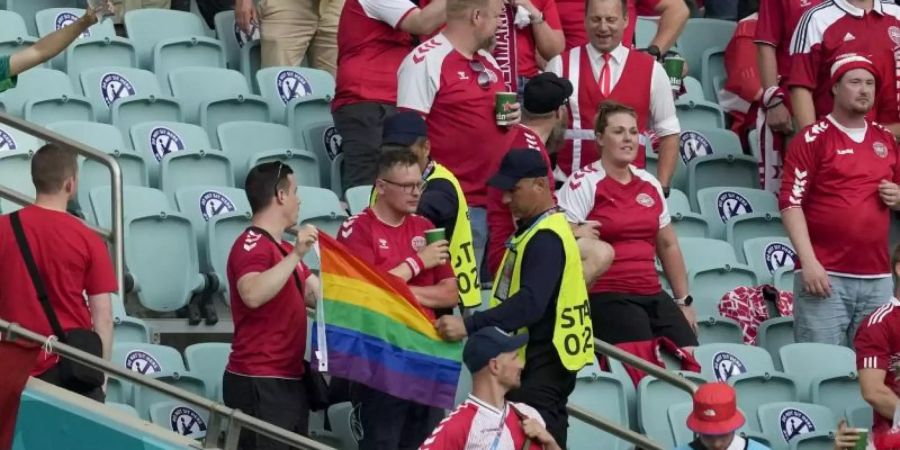 Ordner nehmen zwei Dänemark Fans eine Regenbogen-Fahne ab. Foto: Darko Vojinovic/Pool AP/dpa