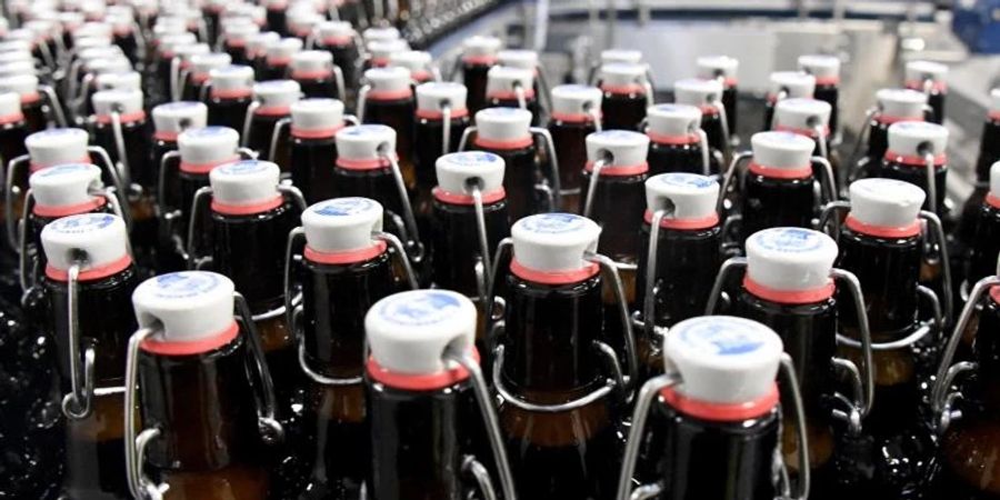 Bierflaschen laufen über ein Band in der Flensburger Brauerei. Foto: Carsten Rehder/dpa