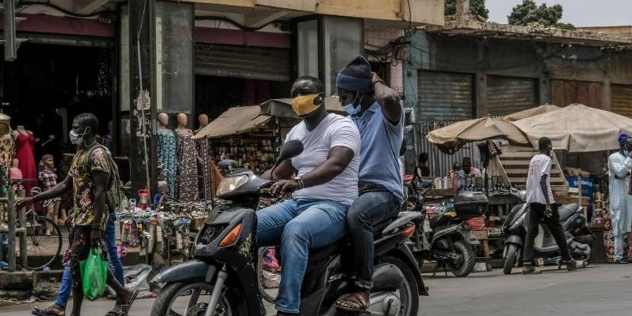 Mit Schutzmaske unterwegs auf dem Motorroller in Dakar. Von der Risikoliste gestrichen wird unter anderem Senegal. Foto: Eddy Peters/XinHua/dpa
