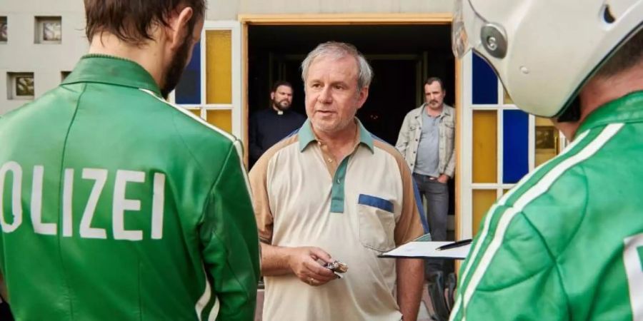 Georg Weiser (Joachim Król, M) im Gespräch mit zwei Polizisten in der Komödie «Endlich Witwer». Foto: Reiner Bajo