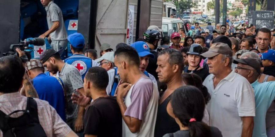 Das Rote Kreuz hat erste Hilfsgüter in Venezuela verteilten dürfen. Hier stehen Menschen in Caracas an für Trinkwasser und Tabletten zur Wasserreinigung. Foto: Ruben Sevilla Brand