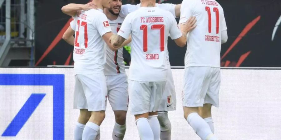 Die Augsburger Finnbogason (l-r), Richter, Schmid und Gregoritsch jubeln. Augsburg hat die Partie in Frankfurt gedreht. Foto: Arne Dedert