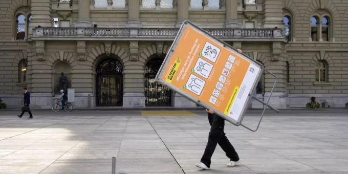 Ein Mitarbeiter installiert ein oranges Hinweis-Schild das BAG vor dem Bundeshaus. Coronavirus Kantone Entwicklung Fallzahlen