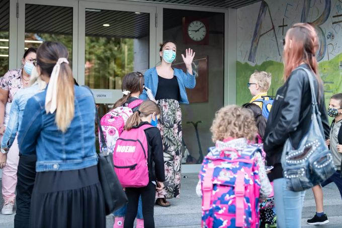 Eine Lehrerin einer Grundschule mit medizinischem Mundschutz begrüsst Schülerinnen und Schüler an ihrem ersten Schultag nach den Ferien. Coronavirus - Schweiz