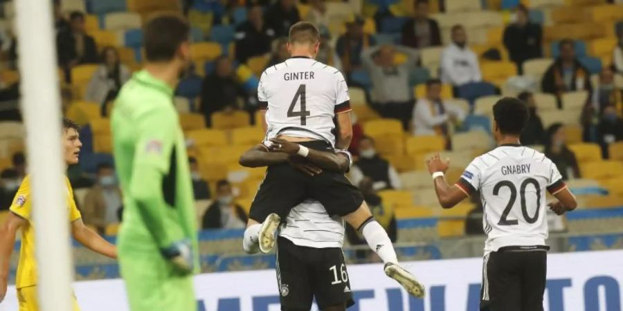 Matthias Ginter, Torschütze zum 1:0, wird von Mannschaftskamerad Antonio Rüdiger beim jubeln hochgehoben - Serge Gnabry kommt zum feiern dazu. Foto: Efrem Lukatsky/AP/dpa