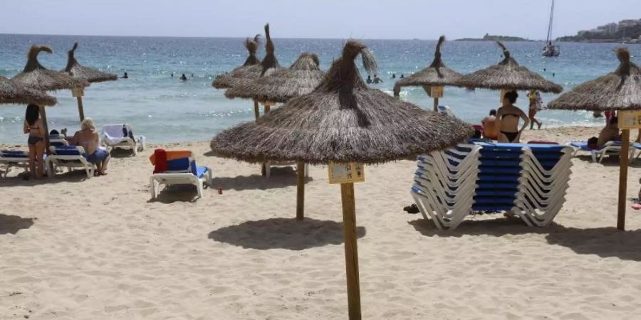 Ein Mann liegt unter einem Sonnenschirm am Strand von Cala Major, Mallorca. Die Bundesregierung warnt vor Reisen auf die Insel. Foto: Clara Margais/dpa