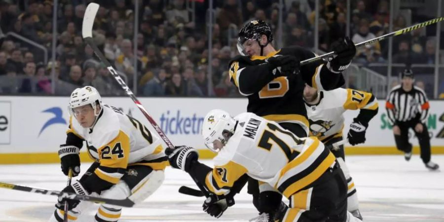Dominik Kahun (l) von den Pittsburgh Penguins und sein Teamkollege Evgeni Malkin (vorn/71) in Aktion gegen Torey Krug (M) von den Boston Bruins. Foto: Mary Schwalm/AP/dpa