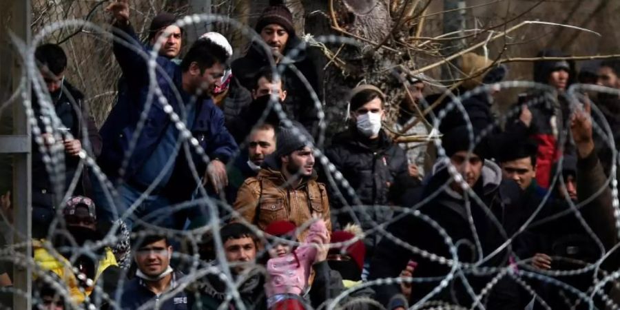 Migranten stehen hinter einem Stacheldrahtzaun nahe des griechisch-türkischen Grenzübergangs von Kastanies. Foto: Giannis Papanikos/AP/dpa