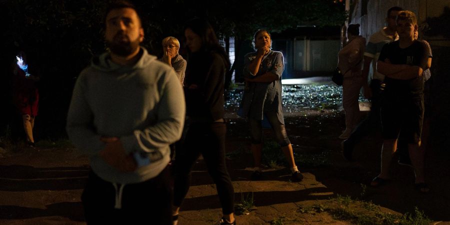 Anwohner stehen vor einem Wohnhaus in Kiew, das bei russischen Luftangriffen beschädigt wurde.