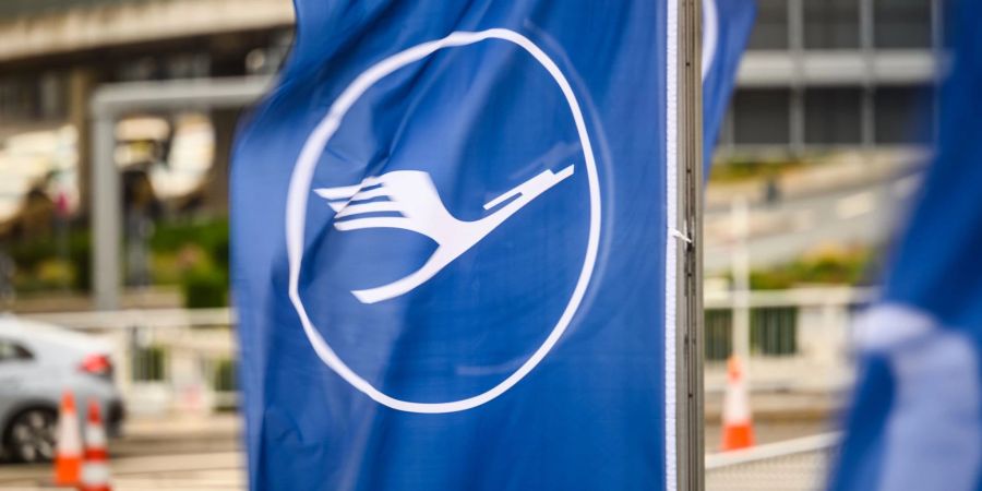 Eine blau-weisse Flagge der Fluggesellschaft Lufthansa flattert am Flughafen in Frankfurt im Wind.