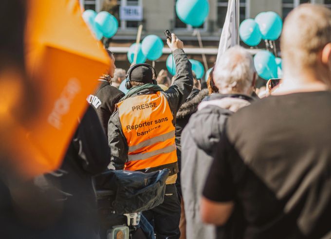 Eine Person trägt eine Leuchtweste mit der Aufschrift «Reporter:innen ohne Barrieren» an einer Aktion für Menschen mit Behinderungen. Auf inclusive-media.ch lässt sich über das Projekt nachlesen. Behinderung Reporter ohne Barrieren