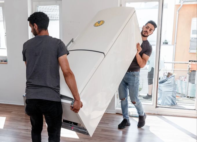 Ob man einen kaputten Kühlschrank ersetzen sollte oder besser reparieren lässt, hängt auch davon ab, wie lange das Gerät bereits genutzt wurde. Männer Umzug Kühlschrank neu Wohnung Möbelpacker