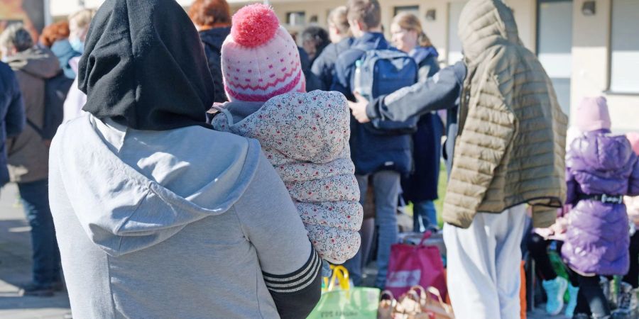 Aus der Ukraine vertriebene Menschen stehen mit ihrem Gepäck vor einem Flüchtlingsheim in Köln.