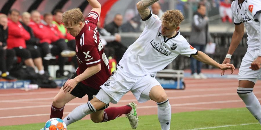 Der Nürnberger Mats Moeller Daehli (l) und Arne Sicker (M) vom SV Sandhausen hakeln an der Auslinie nach dem Ball.