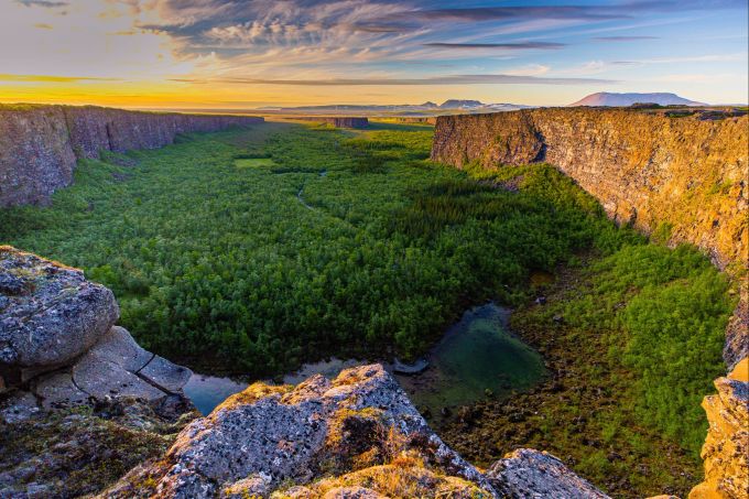 Plötzlich wird es grün: Ásbyrgi ist eine üppige Landschaft, eingebettet in einem hufeisenförmigen Canyon. Canyon Wald Felsen Sonnenuntergang