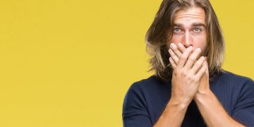 Mann hält sich die Hände vor den Mund