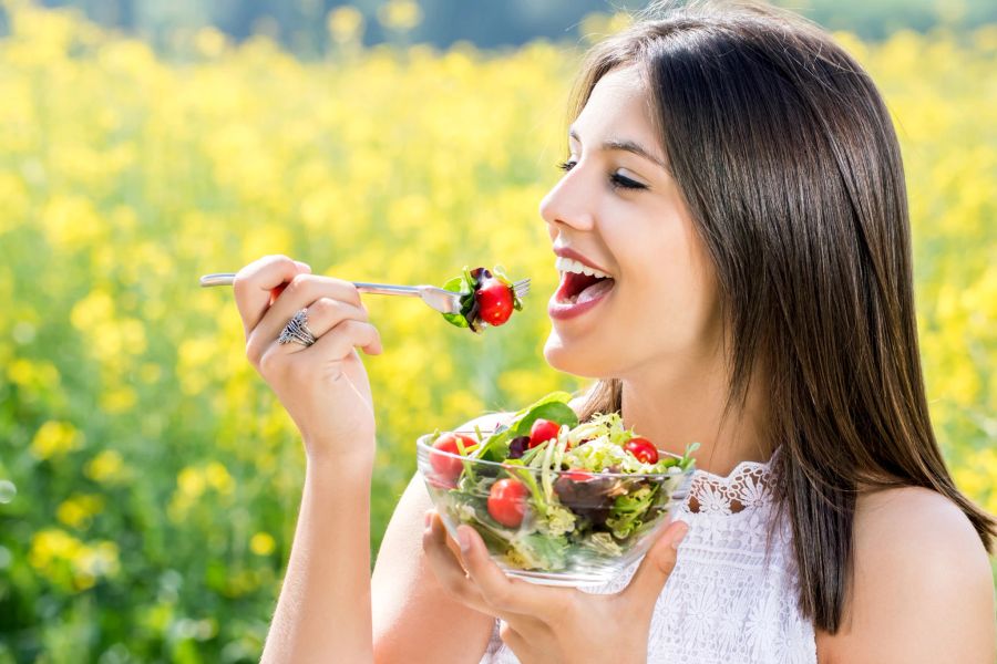 Frau isst Salat in der Natur