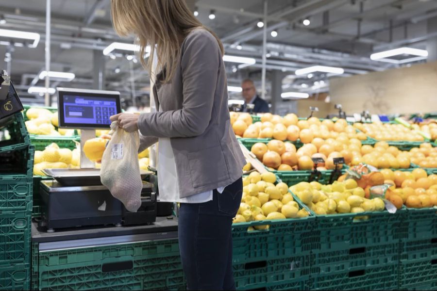 An den Waagen von Coop und Migros werden nun Fragen zur Verpackung gestellt.