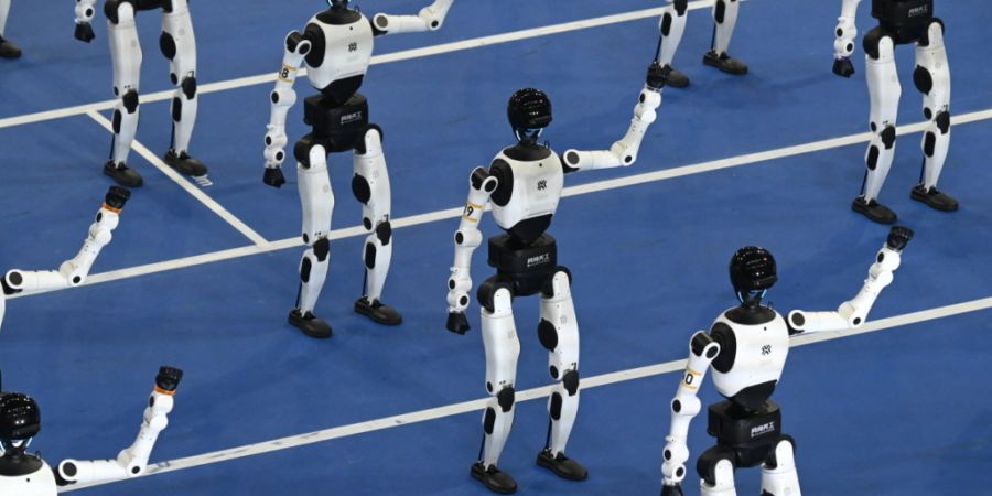 Humanoide Roboter laufen während einer Eröffnungszeremonie der zweiten Ausgabe der World Humanoid ·Robot Games (Weltmeisterschaft humanoider Roboter) in die Eisschnelllaufhalle in de...