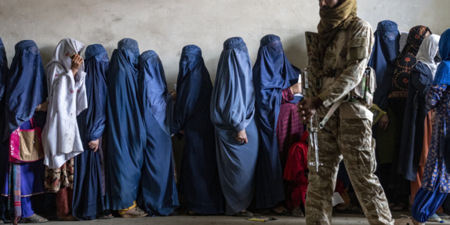 ARCHIV - Ein Taliban-Kämpfer steht Wache, während Frauen in Kabul darauf warten, Lebensmittelrationen zu erhalten, die von einer humanitären Hilfsgruppe verteilt werden. Foto: Ebrahi...