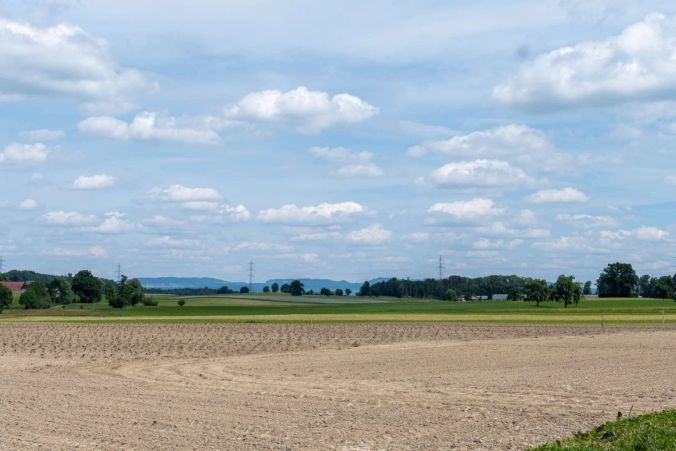 Weisse Wolken über einem Ackerfeld.