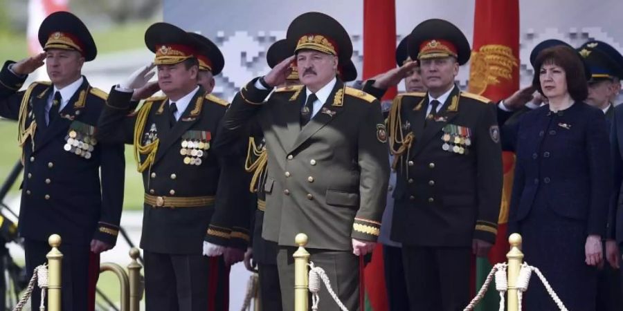 Der weissrussische Präsident Alexander Lukaschenko (M) salutiert, während er die Militärparade in Minsk verfolgt. Foto: Sergei Gapon/Pool AFP/AP/dpa