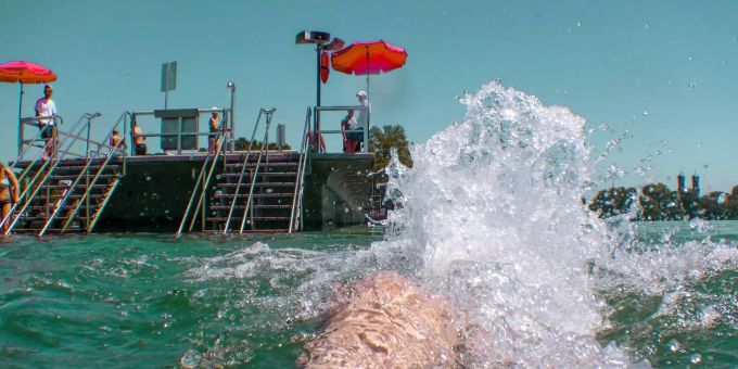 Ein Badegast schwimmt im Bodensee zu einem Floss. Ein Badegast schwimmt im Bodensee zu einem Floss.