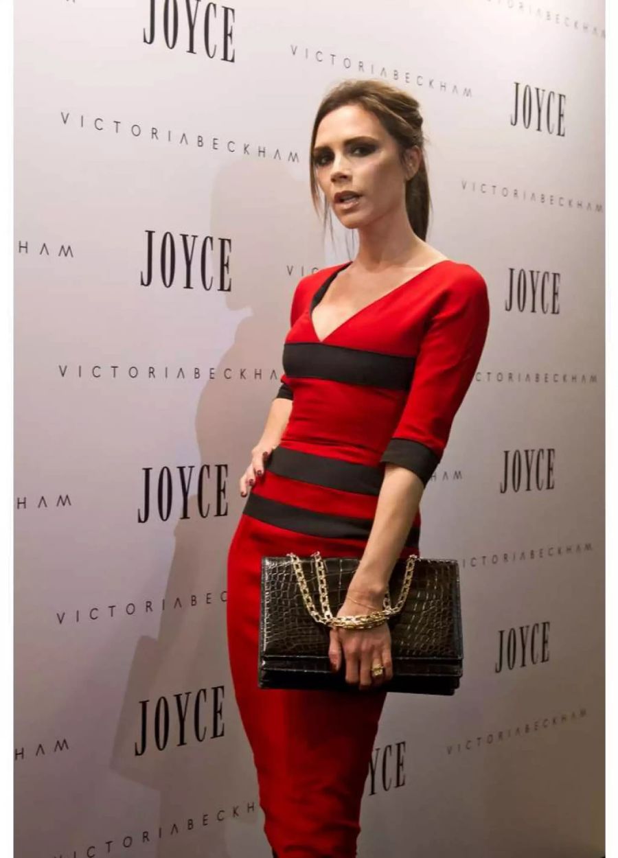 Victoria Beckham posiert mit Kroko-Tasche und im roten Kleid.