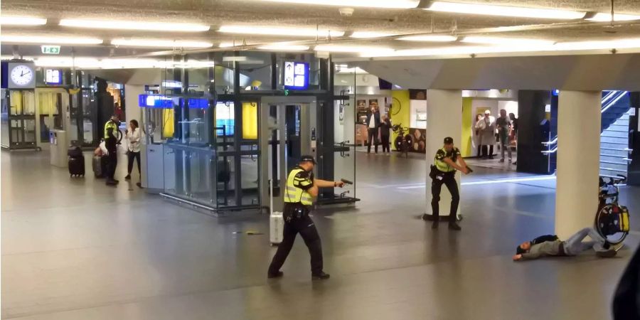 Polizisten richten ihre Waffen auf einen verwundeten 19-jährigen Mann, der von der Polizei angeschossen wurde, nachdem er am Freitag zwei Personen im Hauptbahnhof von Amsterdam niedergestochen hatte.