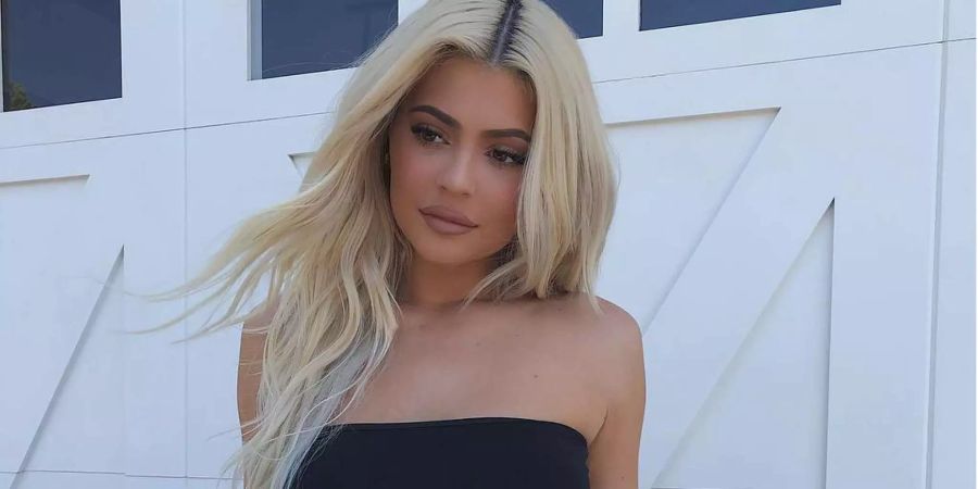 Kylie Jenner sitzt vor einem weissen Garagentor. Sie ist die jüngste Self-Made-Milliardärin der Welt.