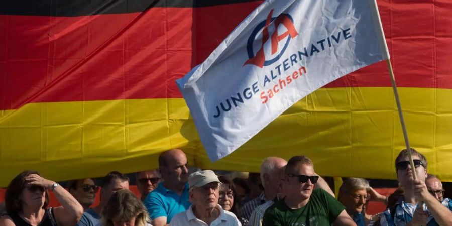 Demonstranten der Jungen Alternative, AfD-Landesverband Sachsen, stehen vor einer Deutschlandflagge.