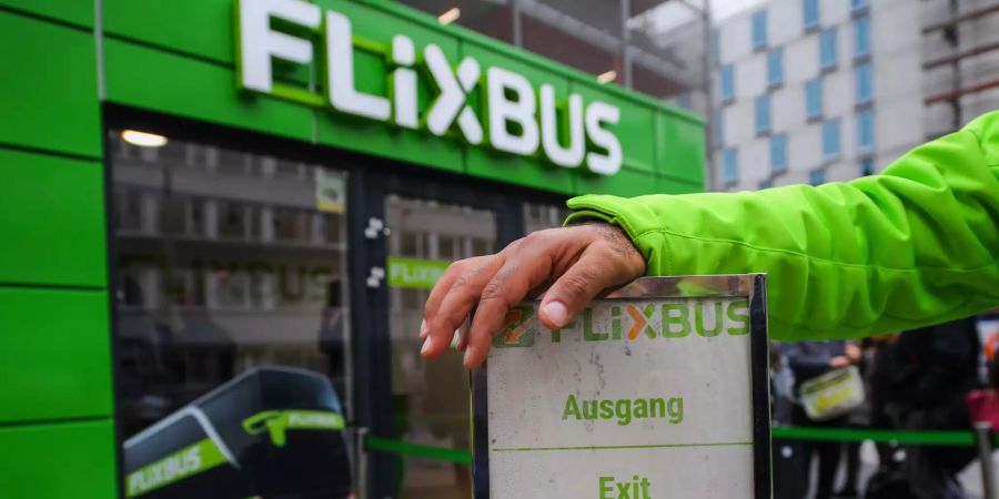 Ein Flixbus-Mitarbeiter legt seine Hand auf das Schild «Ausgang» vor der Kartenverkaufsstelle des Unternehmens.