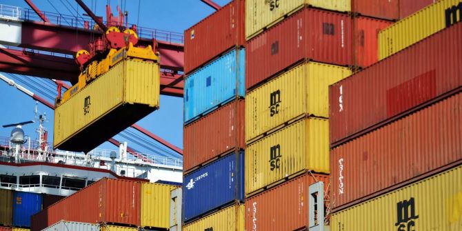 Ein Container wird im Hafen auf ein Containerschiff geladen.