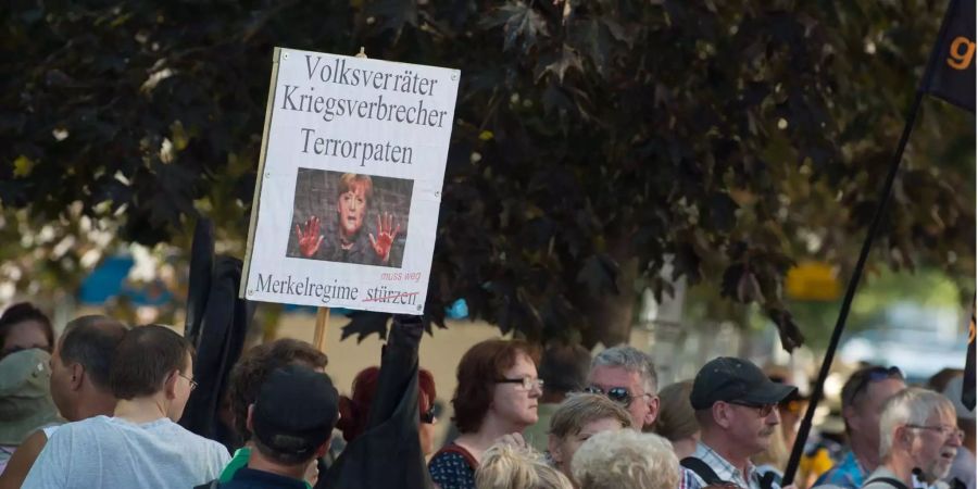 Teilnehmer einer Demonstration der islamfeindlichen Pegida-Bewegung stehen anlässlich des bevorstehenden Besuchs von Bundeskanzlerin Merkel (CDU) im Sächsischen Landtag an einer Strassenkreuzung.