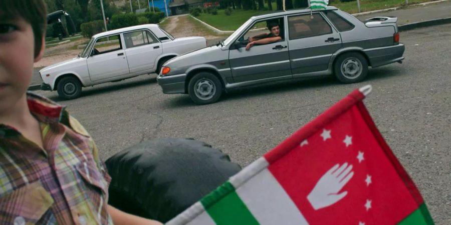 Ein Bürger von Abchasien hält die Landesflagge in der Hand.