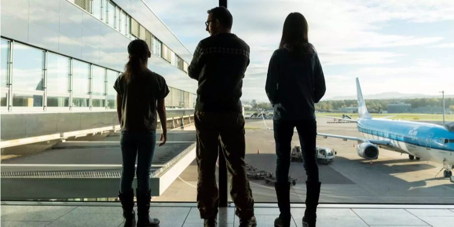 Die Familie sieht zum Fenster hinaus auf den Flugplatz in Zürich Kloten.