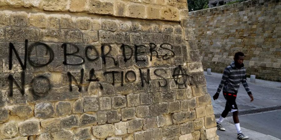 Ein Flüchtling läuft an einem Graffitit vorbei.