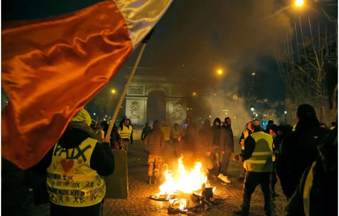 Demonstranten mit gelben Westen stehen neben einem brennenden Fahrrad auf der Champs-Elysees. Zusammenstösse bei erneuten «Gelbwesten»-Protesten