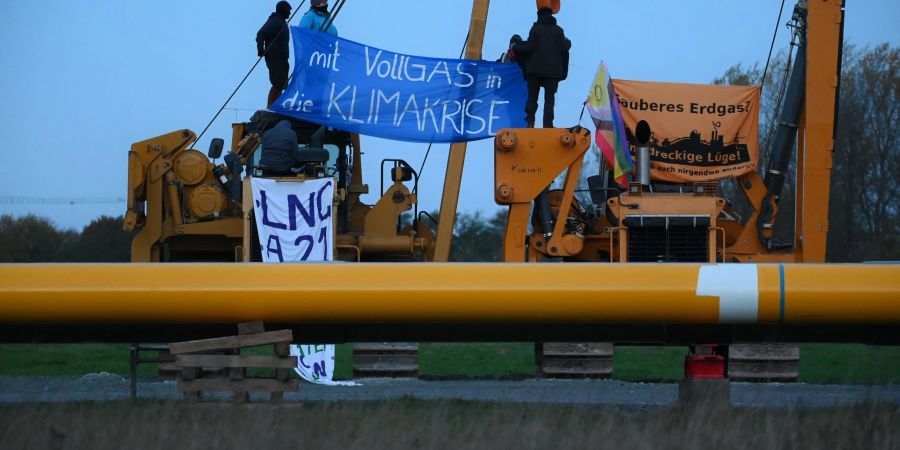 Aktivisten sitzen auf Baufahrzeugen und haben Plakate mit der Aufschrift «mit Vollgas in die Klimakrise» und «Sauberes Erdgas? Eine dreckige Lüge» gespannt.