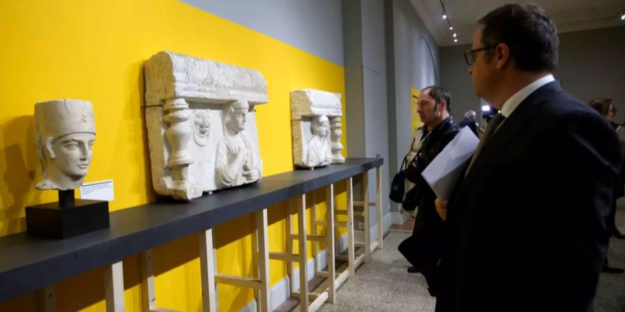 Personen begutachten einige Kunstschätze aus Palmyra in Syrien.